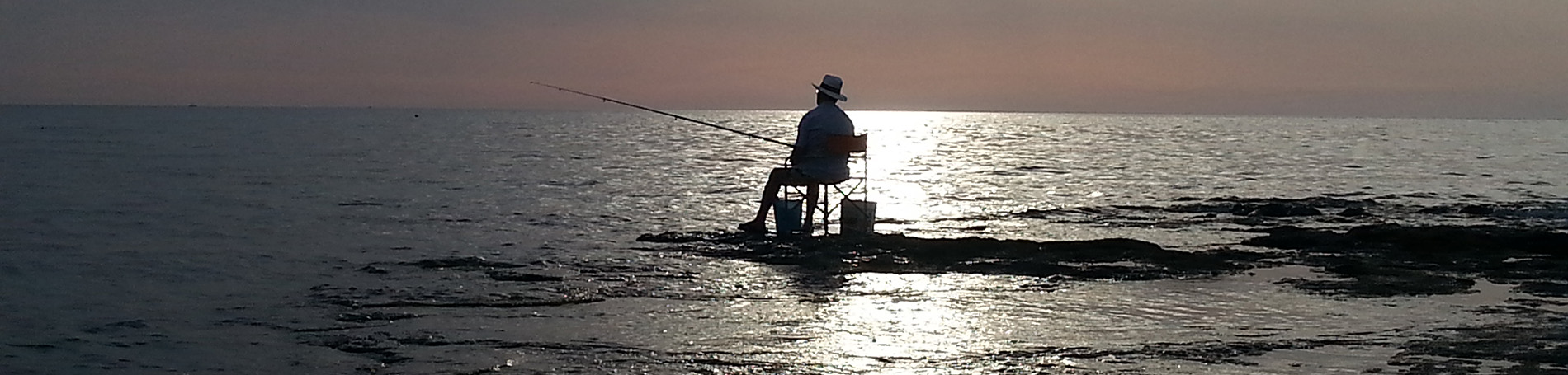 Pescatore con la canna al tramonto Rivabella, Gallipoli, Salento, Lecce.