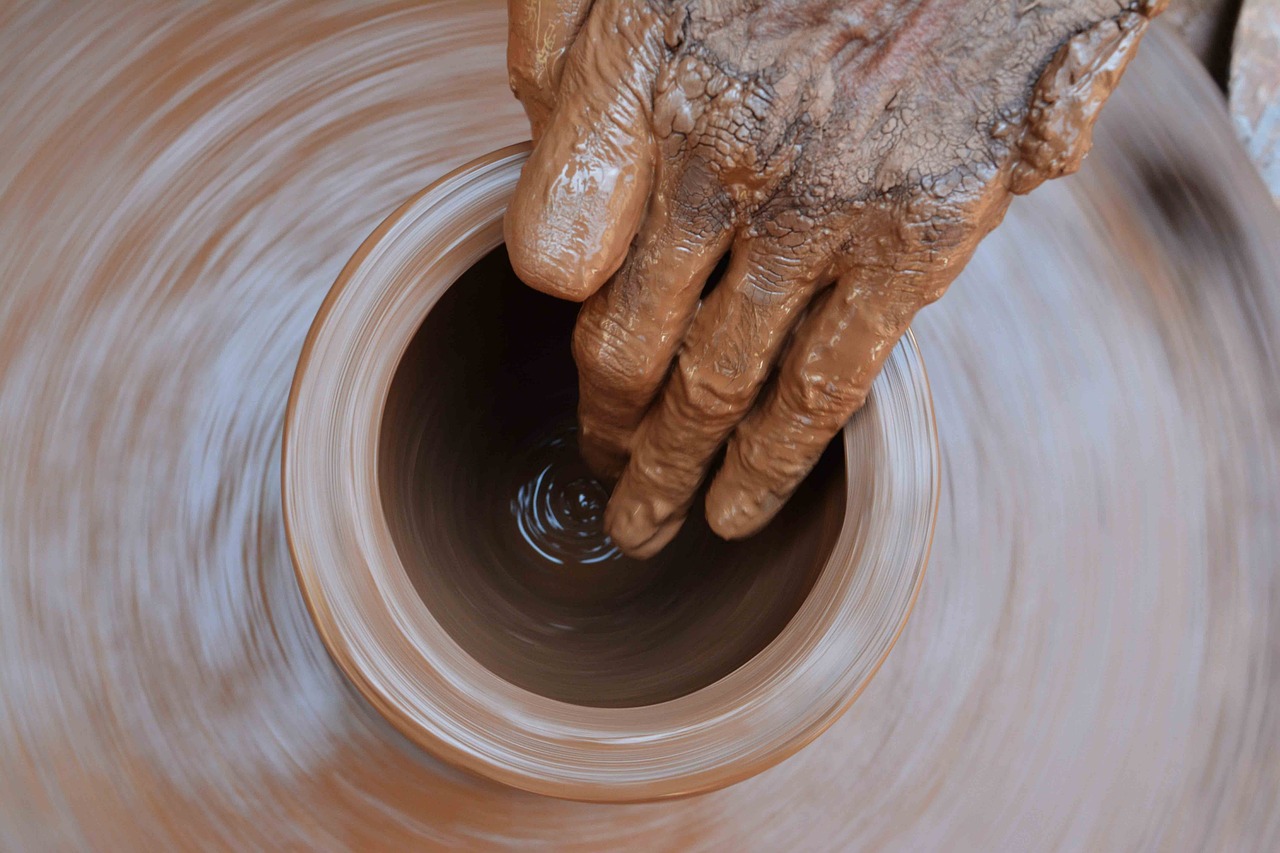 Mani esperte lavorano al tornio un vaso di terracotta.